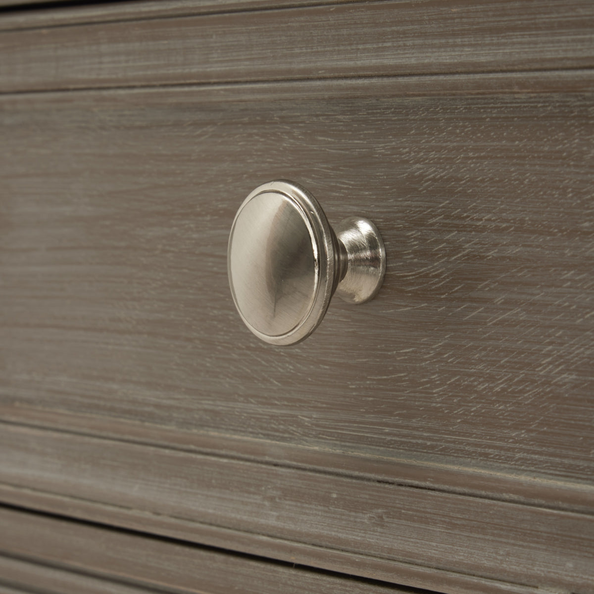 Close-up of the round silver-coloured drawer knob against the pale-streaked grey finish.