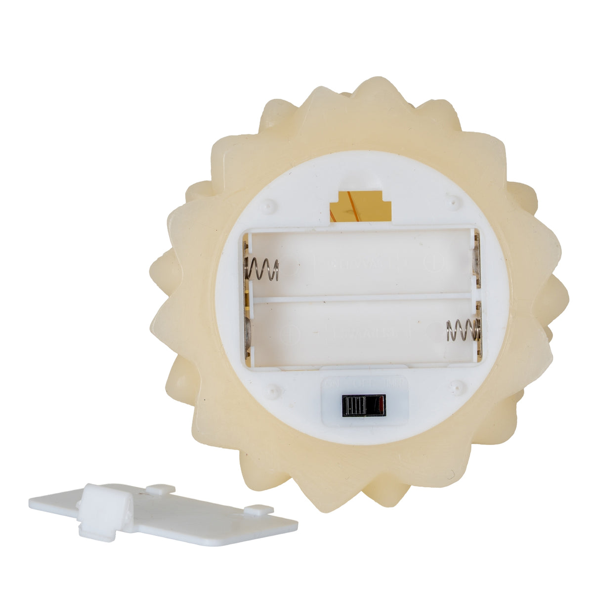 Underside of the cream tree-shaped candle showing an open two-cell battery compartment, spring contacts and a black slide switch, with the detached cover beside it.
