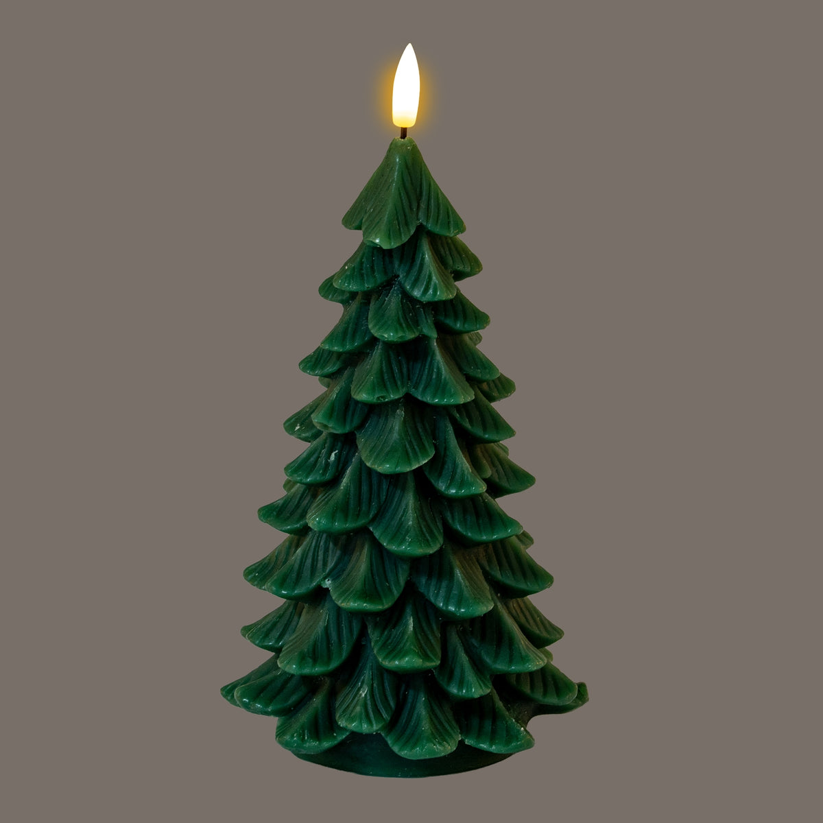Dark-green tree-shaped LED candle against a grey background, pictured with its flame-shaped tip glowing yellow-white above the layered branches.