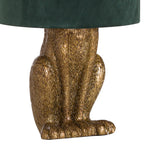 Close-up of the hare lamp's antique-gold torso, bent hind legs and broad sculpted feet beneath the green shade.