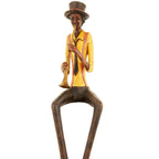 Closer view against white showing the trumpeter’s tall hat, dark tie, hands and gold-toned instrument, with the lower legs cropped.