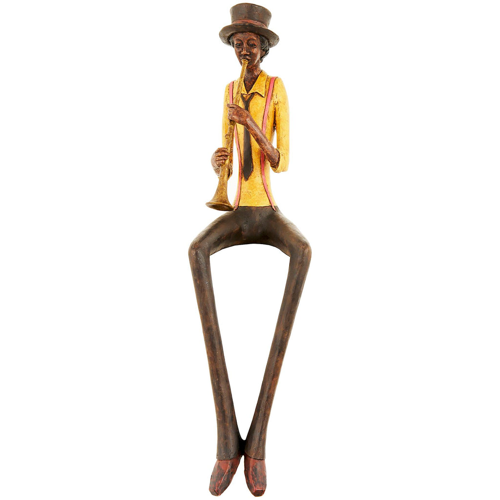 Full view of the seated trumpeter figurine against white, with a yellow shirt, reddish braces and long dark legs ending in pointed shoes.