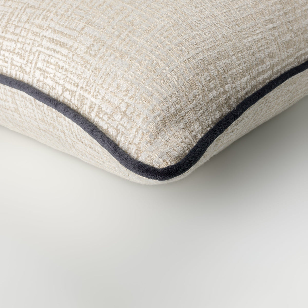 Close-up of the Elara Cushion showing its neutral geometric weave and petrol piping