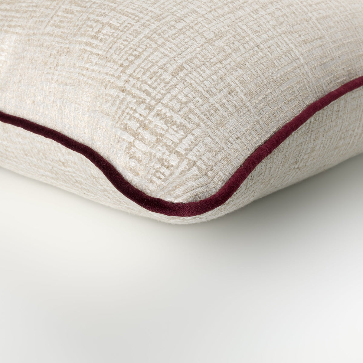 Close-up of the Elara Cushion showing its neutral geometric weave and plum piping
