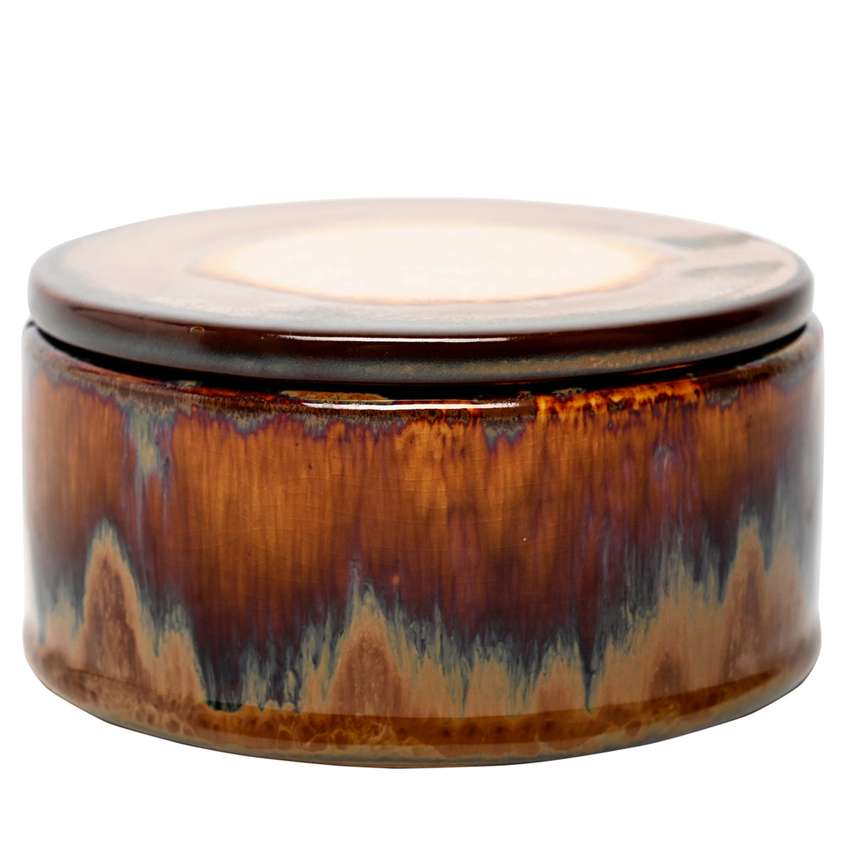 Low, round ochre candle vessel with its lid fitted, showing rust and blue-grey glaze streaks.