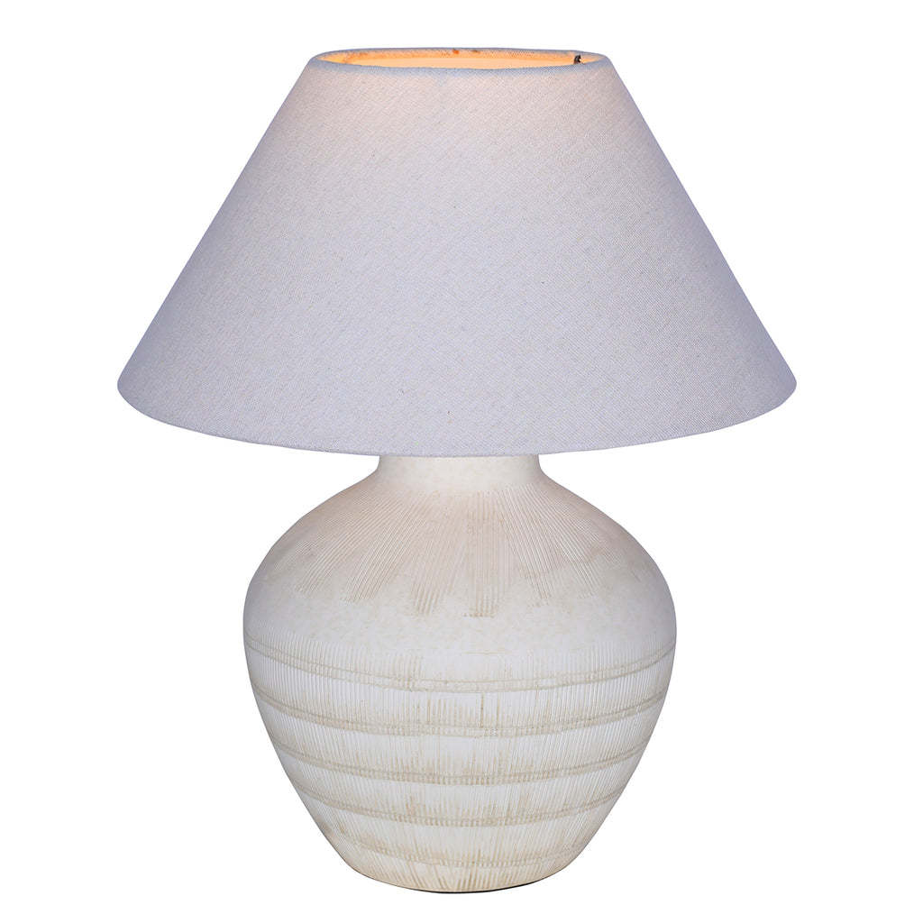 White ceramic table lamp switched on, with a warm glow visible inside the top of its tapered shade.