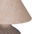 Close-up of the beige hessian shade's open weave and lower edge, with part of the etched brown lamp base beneath.