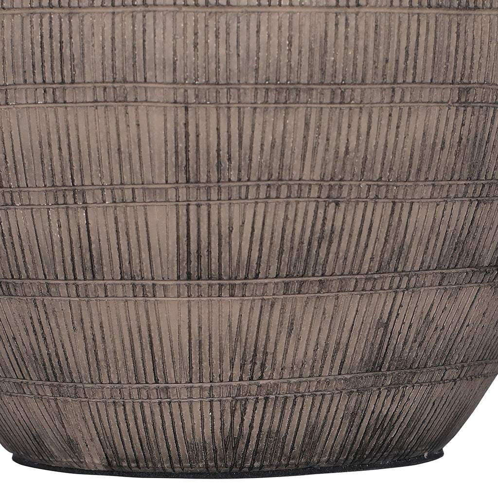 Detail of dark vertical etched strokes divided by horizontal bands across the lower brown ceramic lamp base.