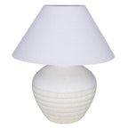 White table lamp with a rounded etched ceramic base and a broad tapered fabric shade against a white background.