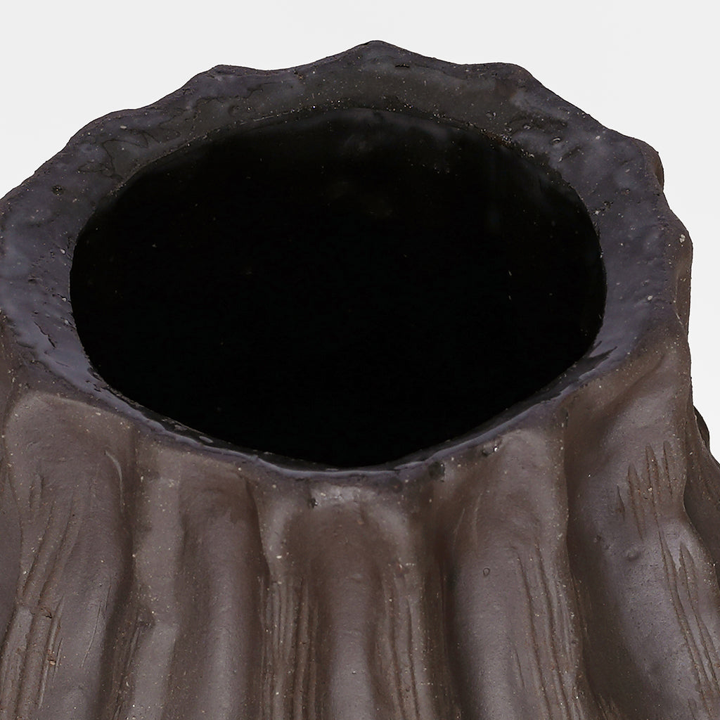 Close view of the vase opening, with an uneven brown rim and dark interior.