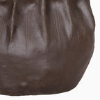 Detail of the vase's lower body, showing fine grooves, angular contours and the brown matte surface.