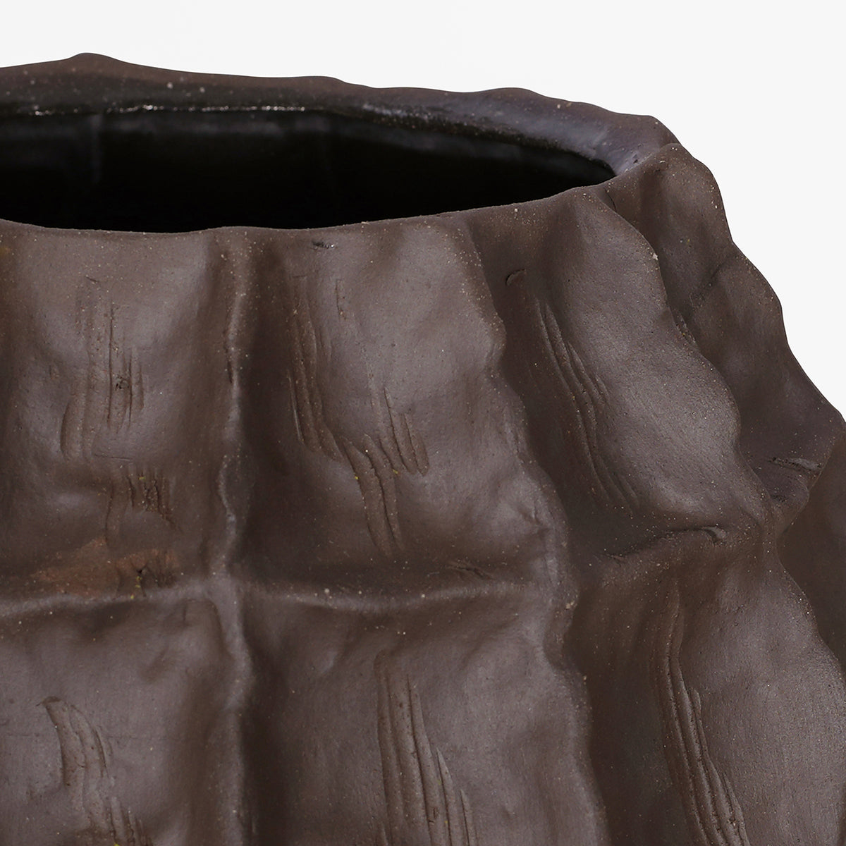 Close-up of the brown vase's upper body and rim, with raised contours and fine scored lines.