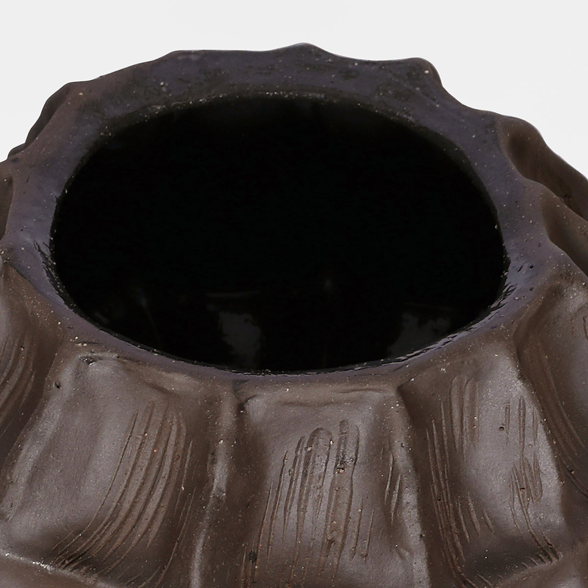 Close view from above of the vase opening and uneven rim, with incised markings on the upper facets.