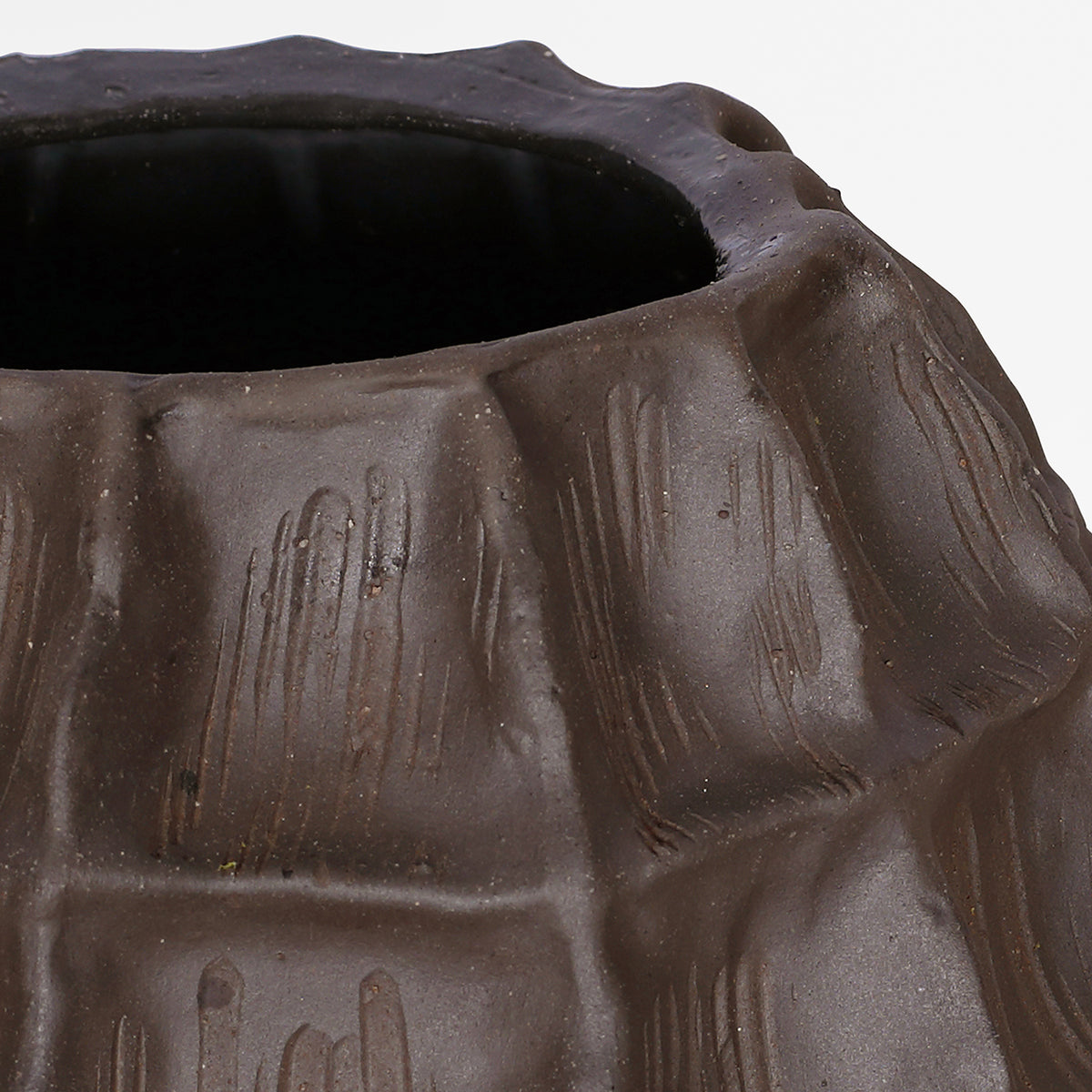 Close-up of the vase's upper brown facets, textured matte surface and curved incised lines.