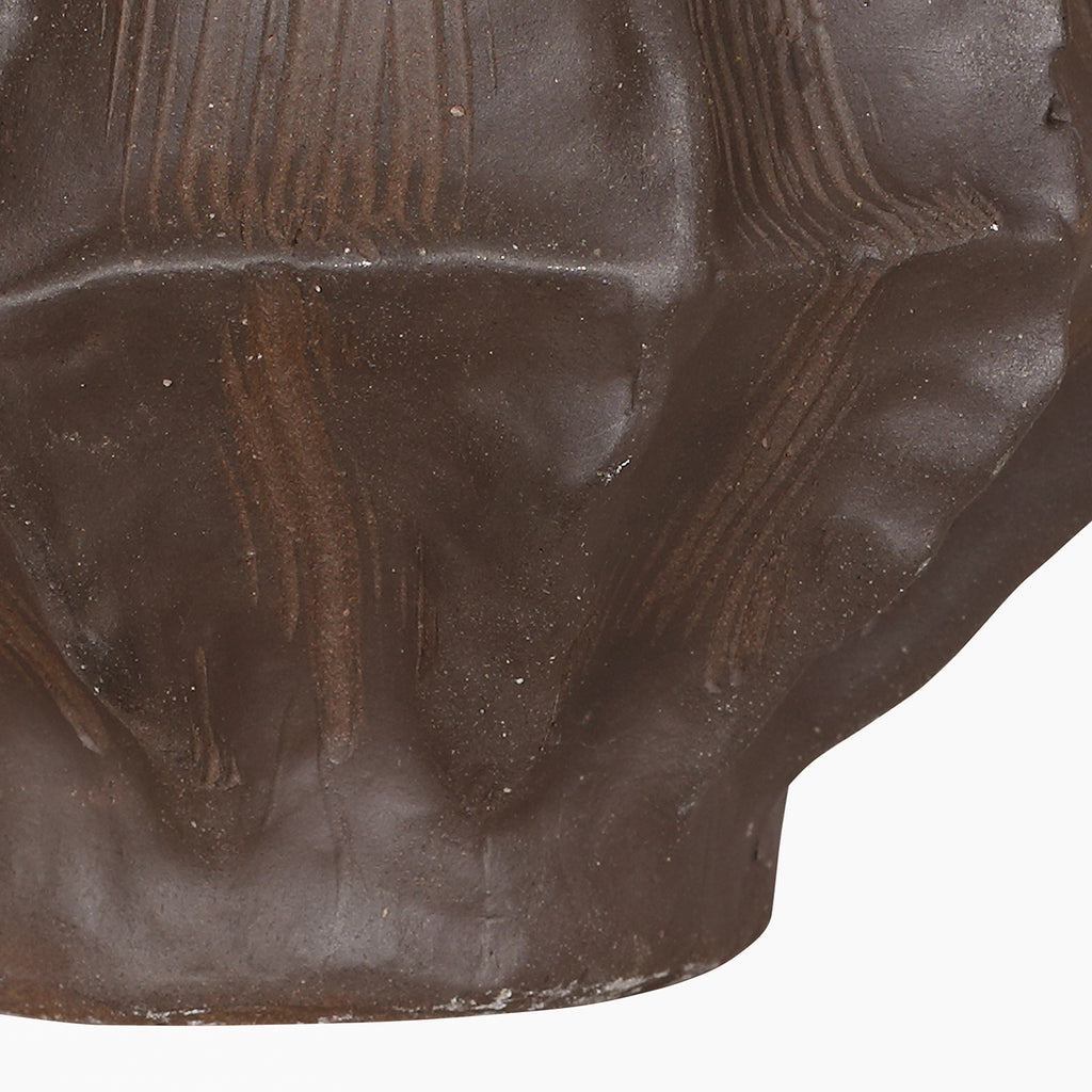 Detail of the lower faceted body and base, showing fine surface speckles and incised lines.