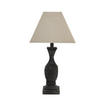 Unlit table lamp with a pale tapered square shade, dark faceted waist and stepped square foot against white.