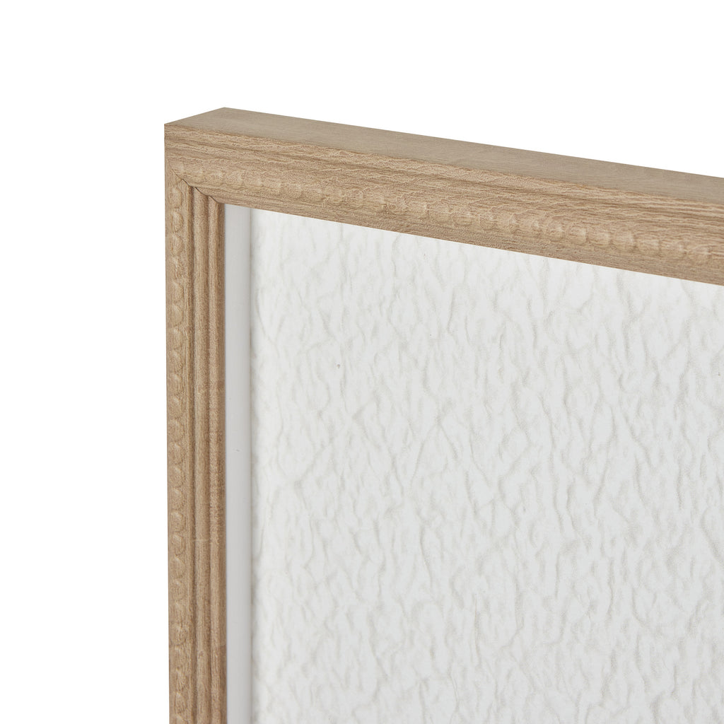 Angled detail of the artwork's upper frame corner, showing warm-beige beading beside the rippled white surface.