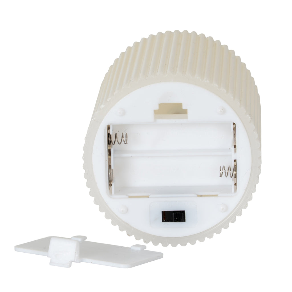 Underside of the ribbed candle showing an open battery compartment with spring contacts, a black sliding switch and the detached white cover below.