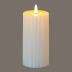 Ribbed LED pillar candle pictured against a grey background, with a bright flame-shaped element and a yellow glow around the recessed top.