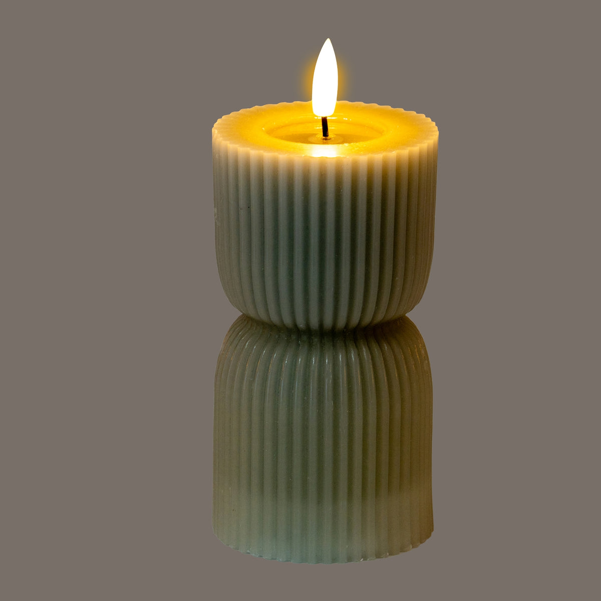 Ribbed hourglass LED candle pictured with a bright flame-shaped element and yellow light around the recessed top against a grey background.