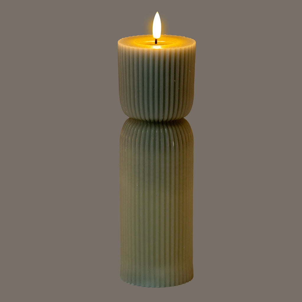 Grey-green ribbed LED candle pictured illuminated against a grey background, with a bright flame-shaped top and a yellow glow around the recessed rim.