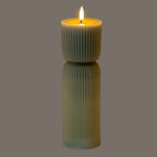 Grey-green ribbed LED candle pictured illuminated against a grey background, with a bright flame-shaped top and a yellow glow around the recessed rim.