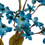 Close-up of blue petals with pale streaks and dark centres, surrounded by small buds and crossing brown branches above an olive-green leaf.