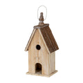 Three-quarter front view of the birdhouse, showing its pale washed body, dark pitched roof, square plinth and finial beneath a pale loop.