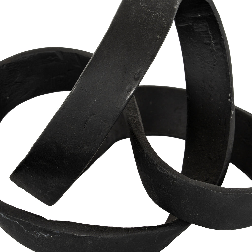 Close-up of the knot ornament's crossing black bands, showing textured surfaces and subtle lighter marks.