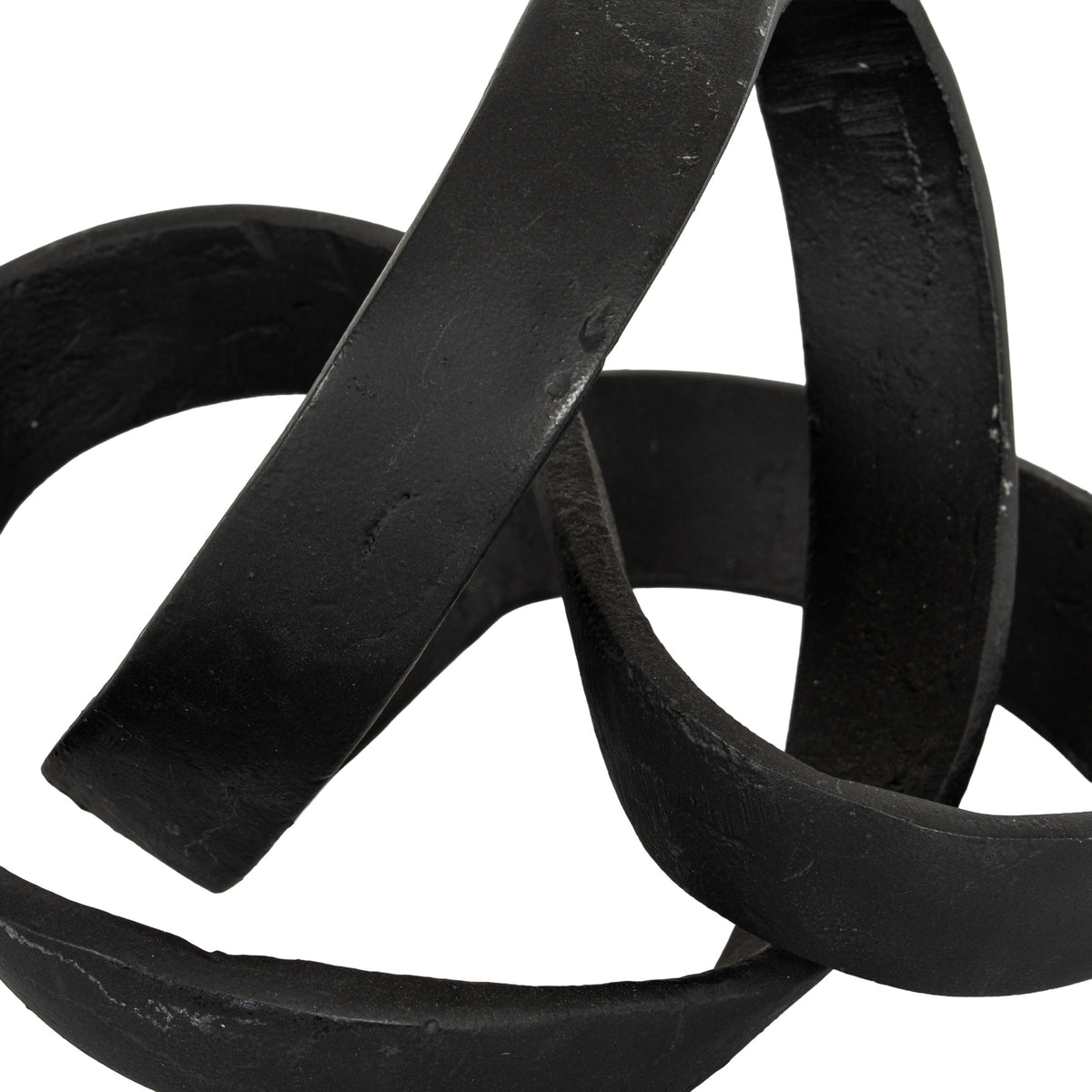 Close-up of the knot ornament's crossing black bands, showing textured surfaces and subtle lighter marks.