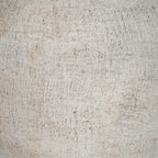 Detail of the vase's granular cream surface, showing scattered dark flecks and irregular horizontal and vertical marks.