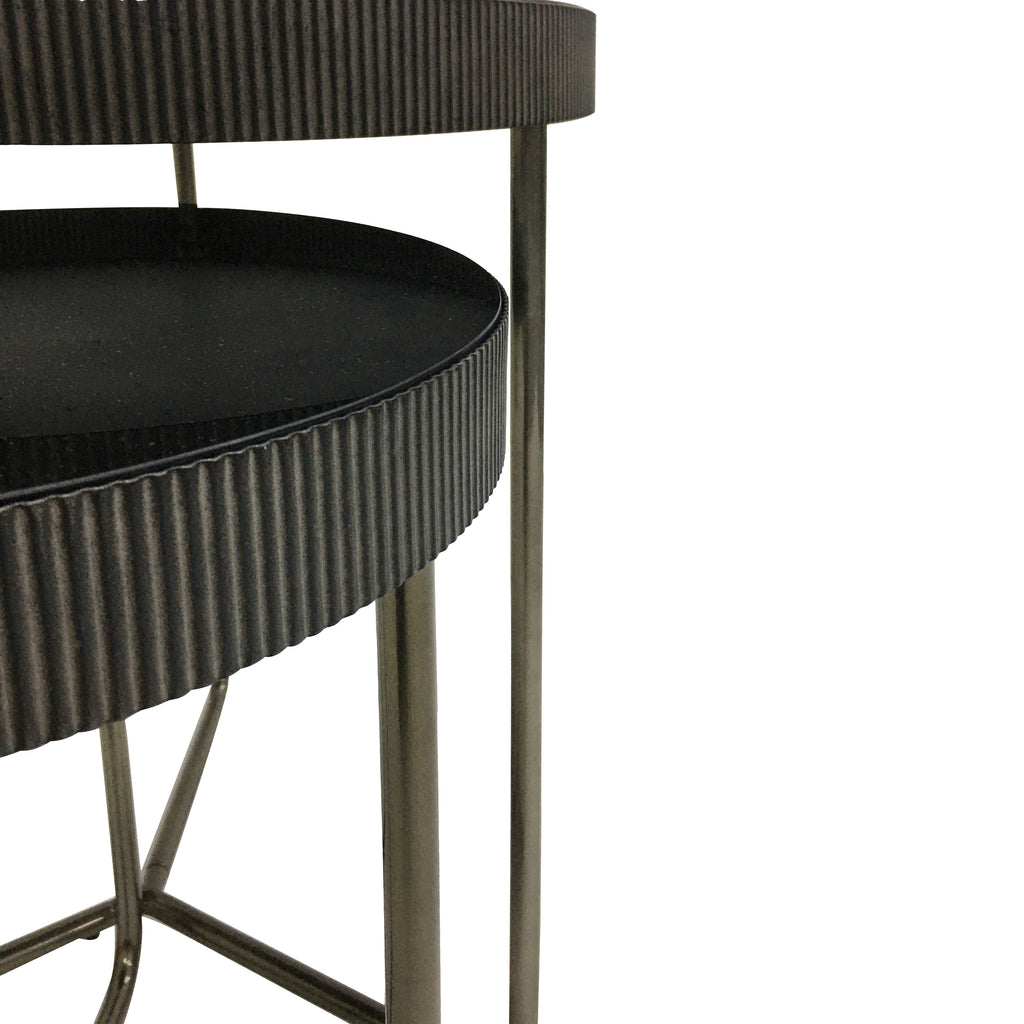 Close view of the overlapping tables showing the vertical fluting around their dark glass tops and the slim metal legs.