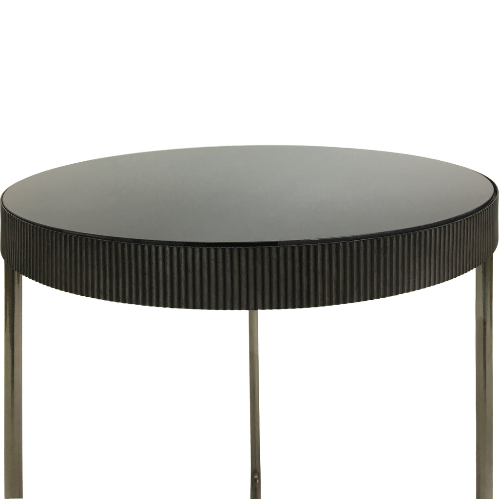 Detail of a round black-tinted mirrored tabletop and its textured fluted rim, with the upper sections of the legs below.