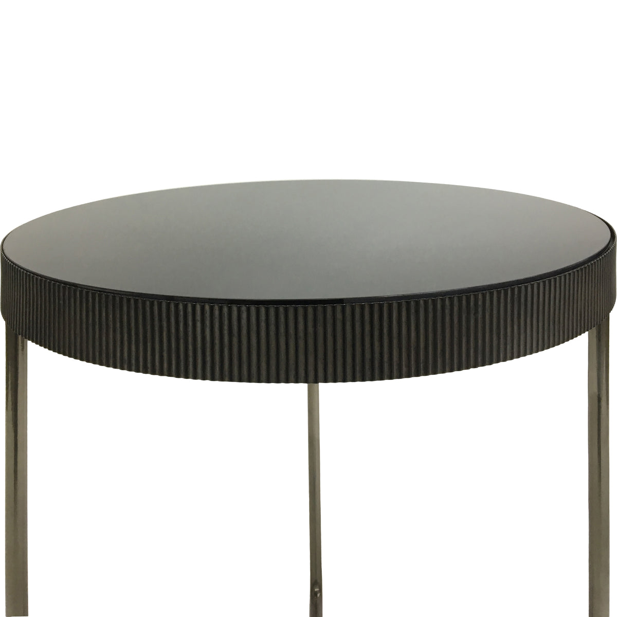 Detail of a round black-tinted mirrored tabletop and its textured fluted rim, with the upper sections of the legs below.