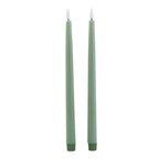 Two slim sage green LED dinner candles with pale flame-shaped inserts and darker ribbed base caps against white.