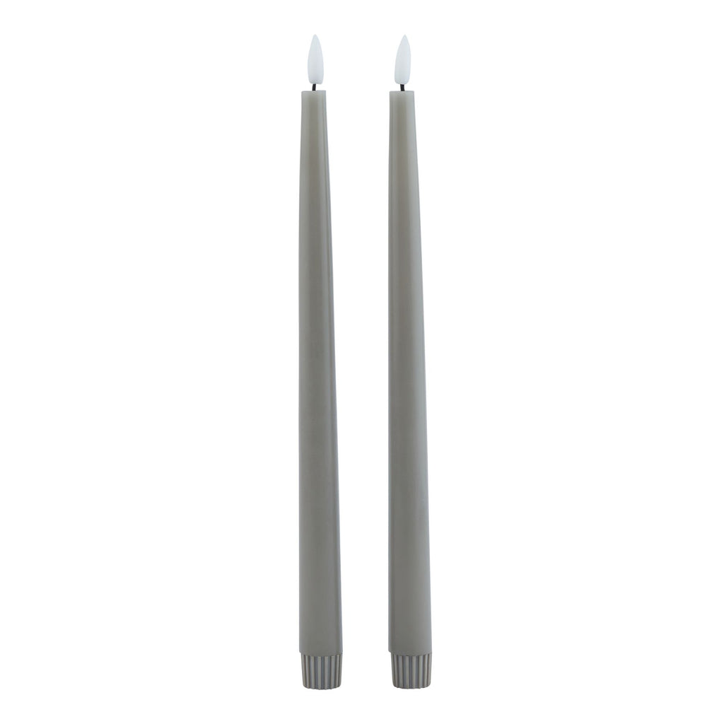 Two slim grey dinner candles shown in full against white, with white flame-shaped tips and ribbed lower sleeves.
