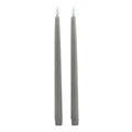 Two slim grey dinner candles shown in full against white, with white flame-shaped tips and ribbed lower sleeves.