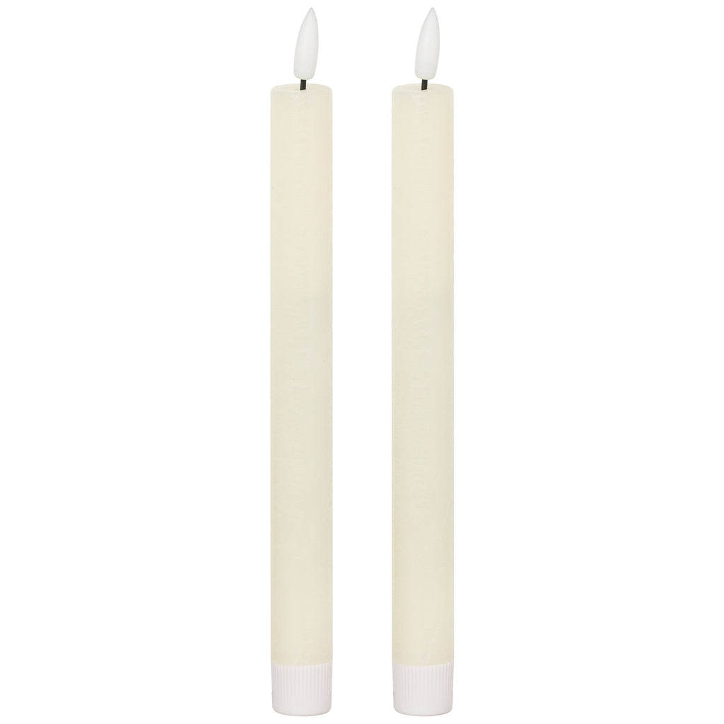 Two matching slender ivory dinner candles with white flame-shaped tips on dark posts and ribbed white lower sleeves, against a white background.
