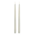 Full-length view of two pale LED dinner candles with fluted lower caps and flame-shaped inserts pictured with warm white centres.