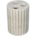 White marble toothbrush holder viewed at an angle, showing vertical fluting and three round openings in the top.