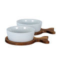Two glossy white bowls on brown fish-shaped trays, viewed from a low angle with both forked tails pointing right.