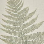 Close-up of the fern's finely divided green leaflets against the cream woven texture.