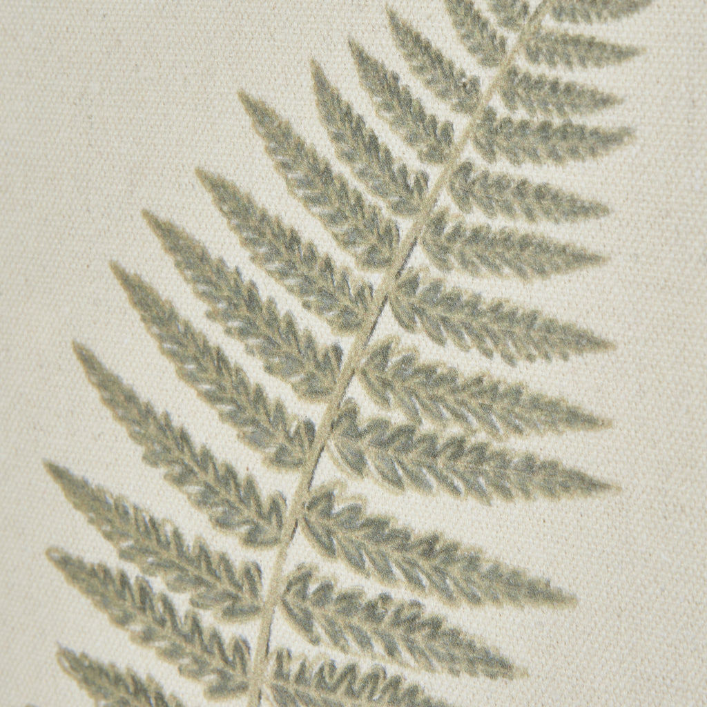 Close-up of muted green fern leaflets and the fine woven texture of the cream background.