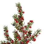 Close-up of the tree's upper branches showing olive-green needle-like foliage, glossy red berries, scattered black berries and granular white frosting.