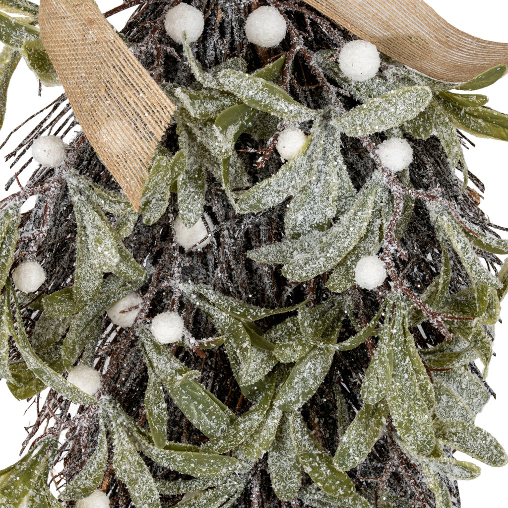 Close-up of white frost texture and reflective flecks on olive-green leaves and dark twiggy forms, with round white berries and open-weave tan ribbon.