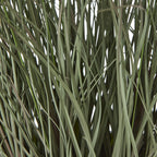 Detail of densely overlapping muted green artificial grass blades, with thin stems crossing between them.