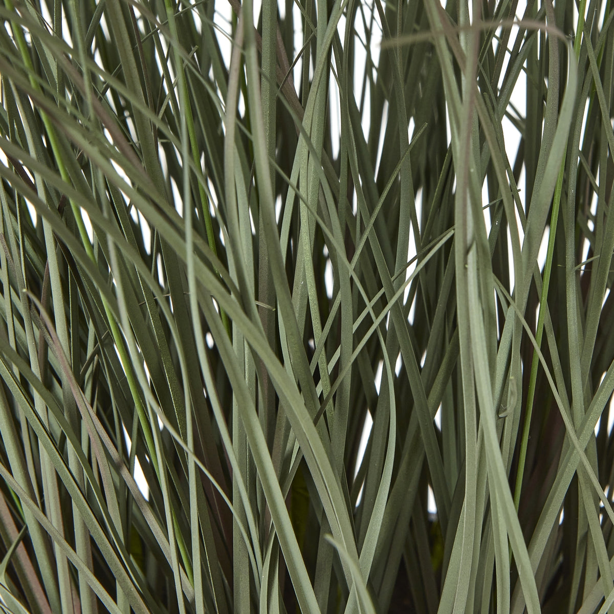 Detail of densely overlapping muted green artificial grass blades, with thin stems crossing between them.