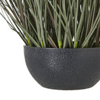 Close-up of the pebbled black bowl-shaped pot beneath the lower green blades of the artificial grass arrangement.