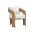 Three-quarter view of the Natural Geometric Weave Dining Chair, showing curved woven arms, broad wicker-wrapped legs and cream seat and back cushions on a white background.