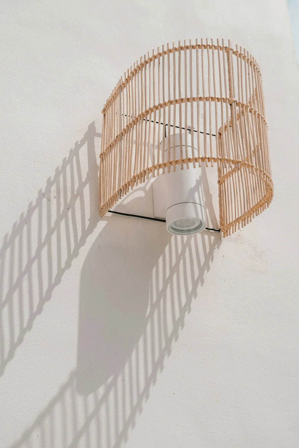 Gigi Rattan Wall Applique – Natural, Small – wall-mounted view casting a curved rattan shadow
